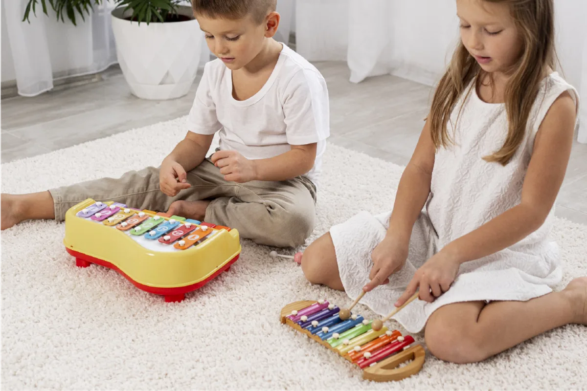 Two children playing xylophones together on a living-room rug